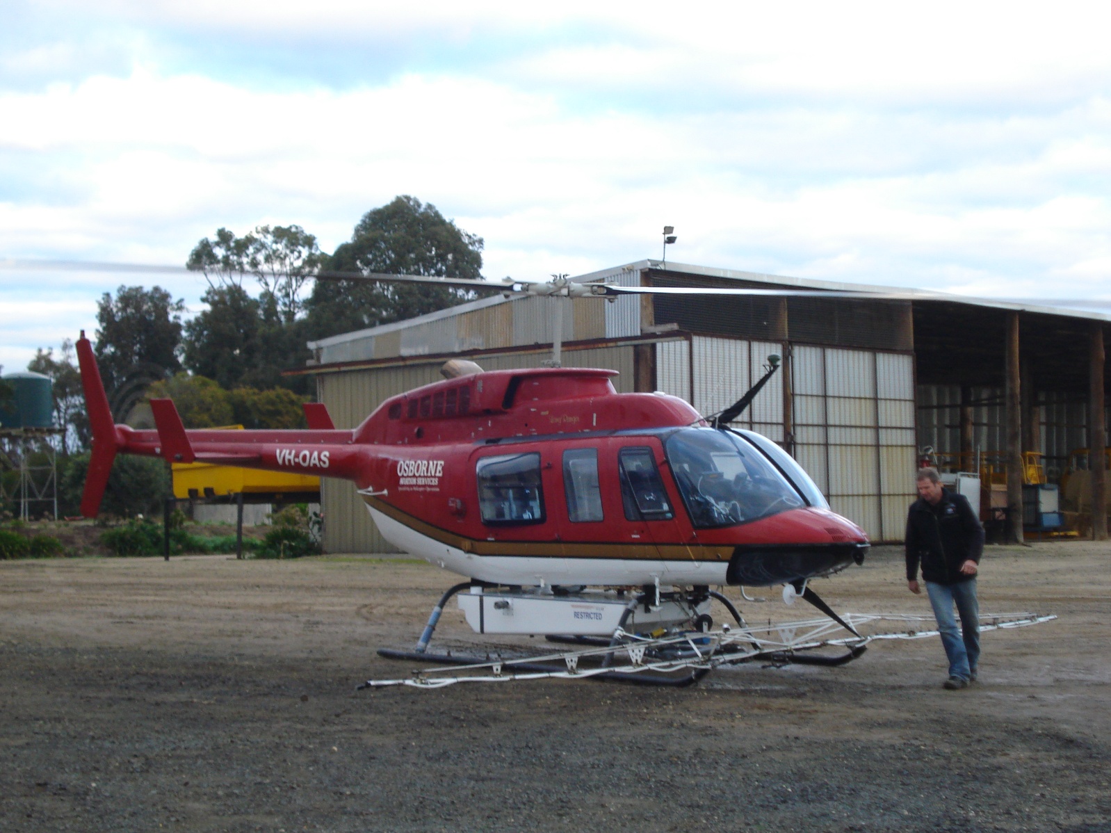 Red Bell helicopter parked outside a hangar with a man walking alongside